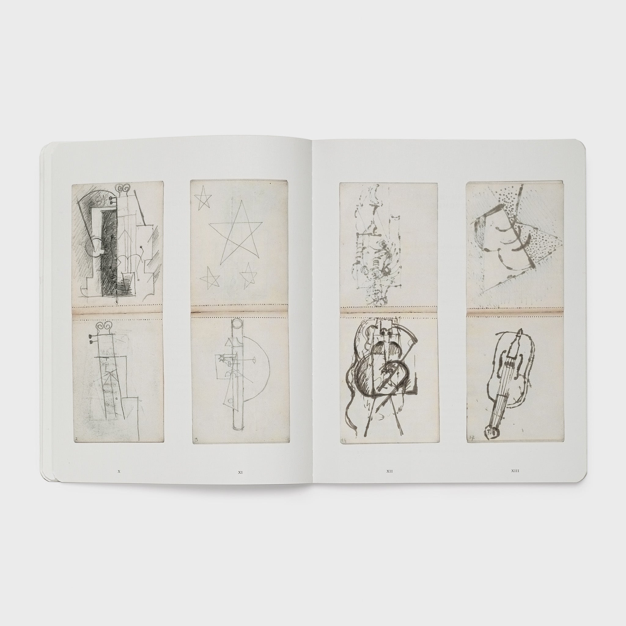 The book is open to two pages. There are four images of the artists notebook across both pages.