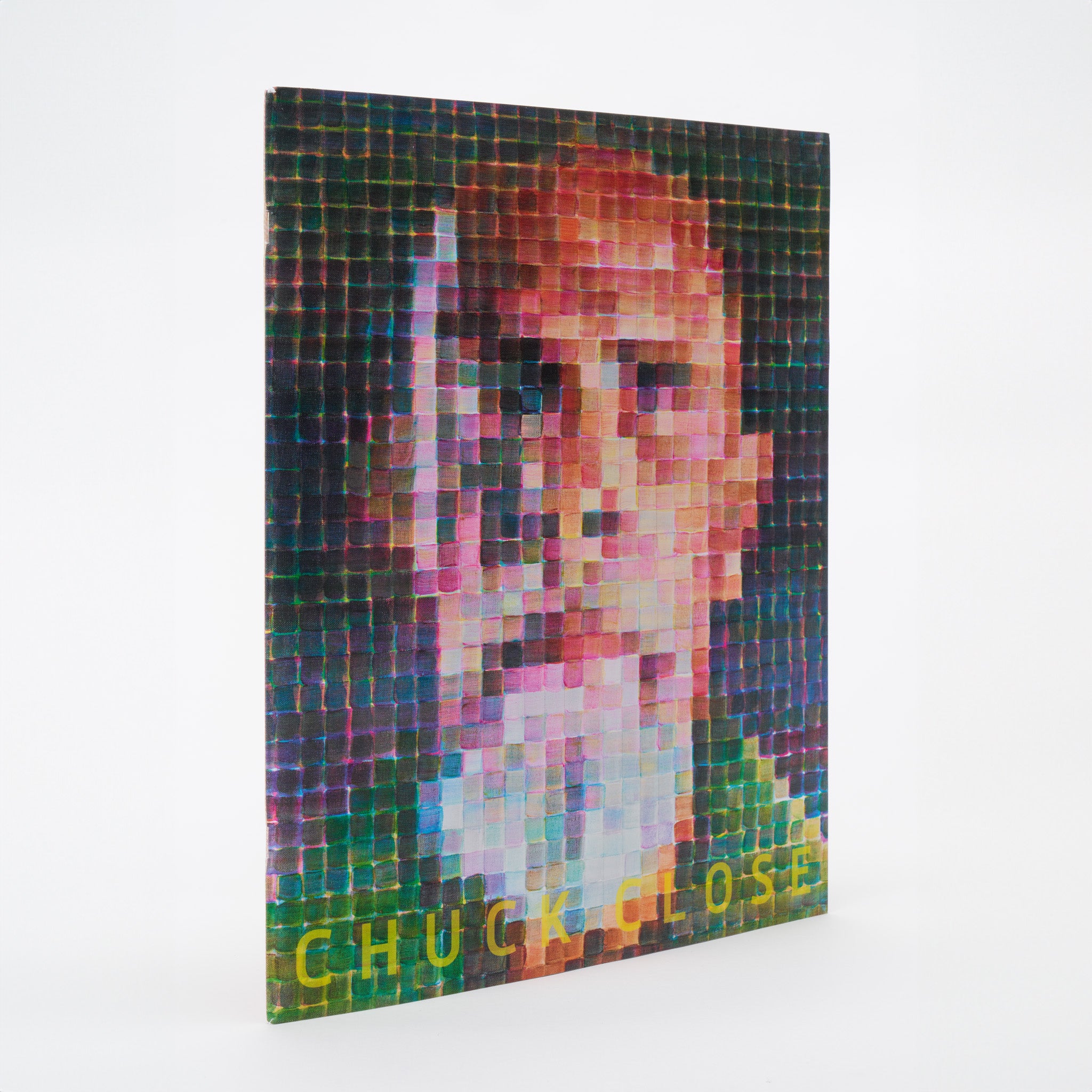 Chuck Close. The book is standing upright and features a Chuck Close self portrait with yellow text.