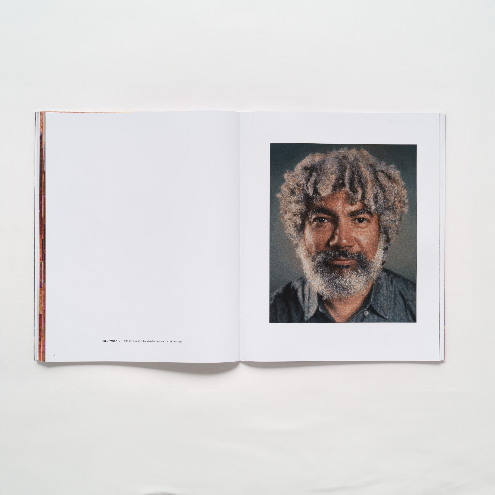 The book is open to two pages, there is a portrait of Fred Wilson on a tapestry on the right page and the left page has a description of the work in small black font.