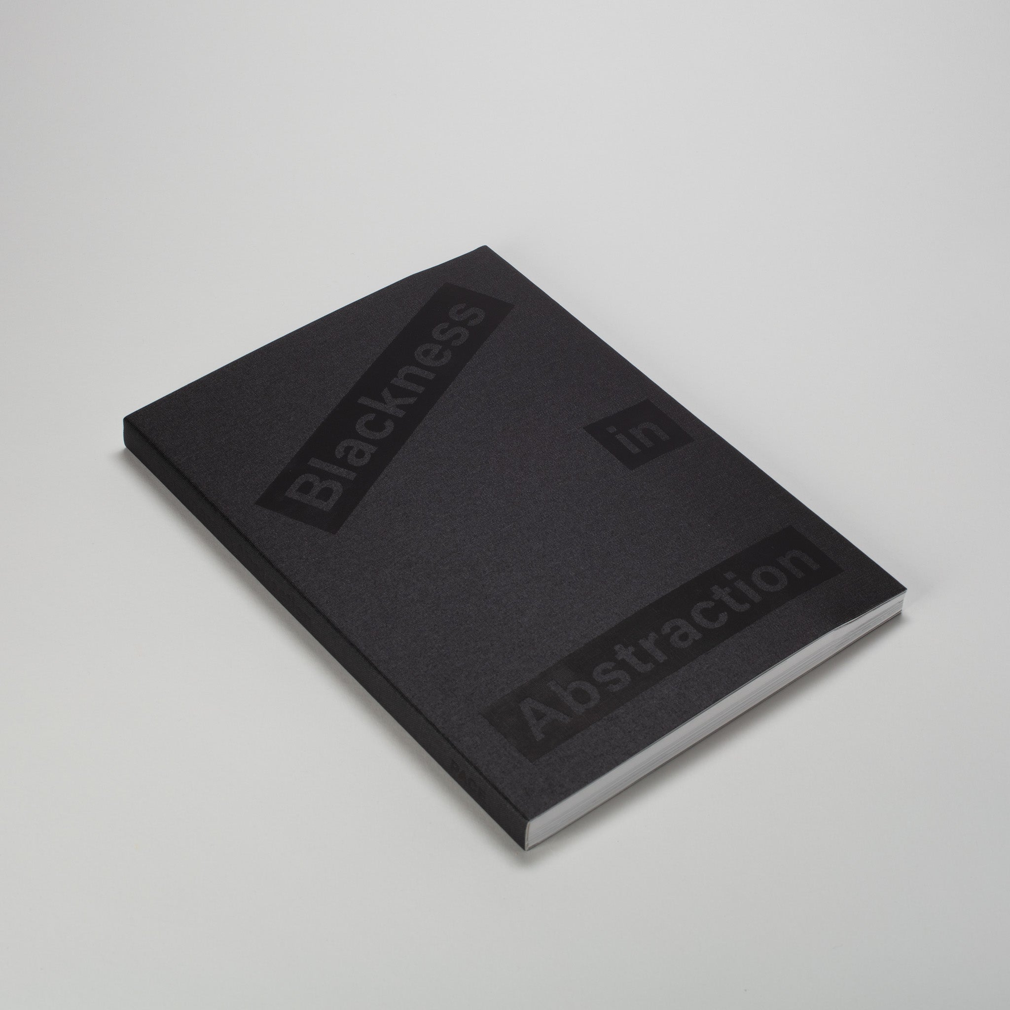Blackness in Abstraction. The book is laying flat and has a black cloth cover with black font.