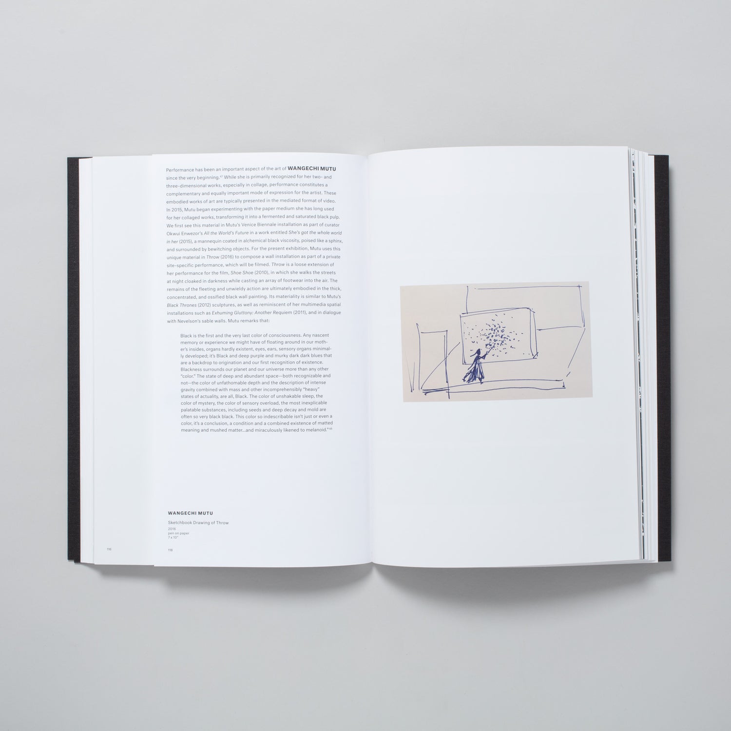 The book is open to two pages. The left page has an essay about Wangechi Mutu and the right page has an image of her drawing.