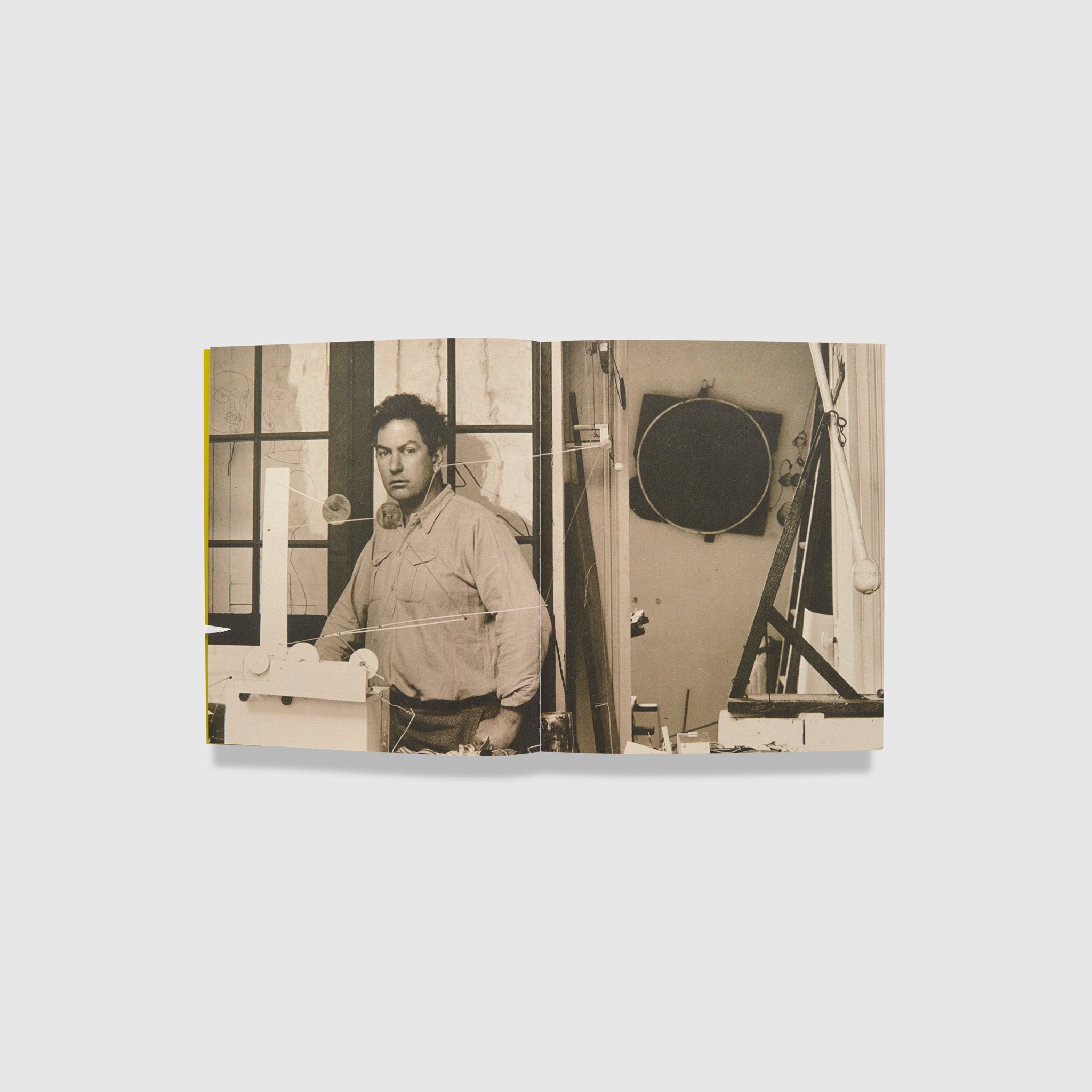 The book is open to two pages with a sepia photo of Alexander Calder in his studio across both.