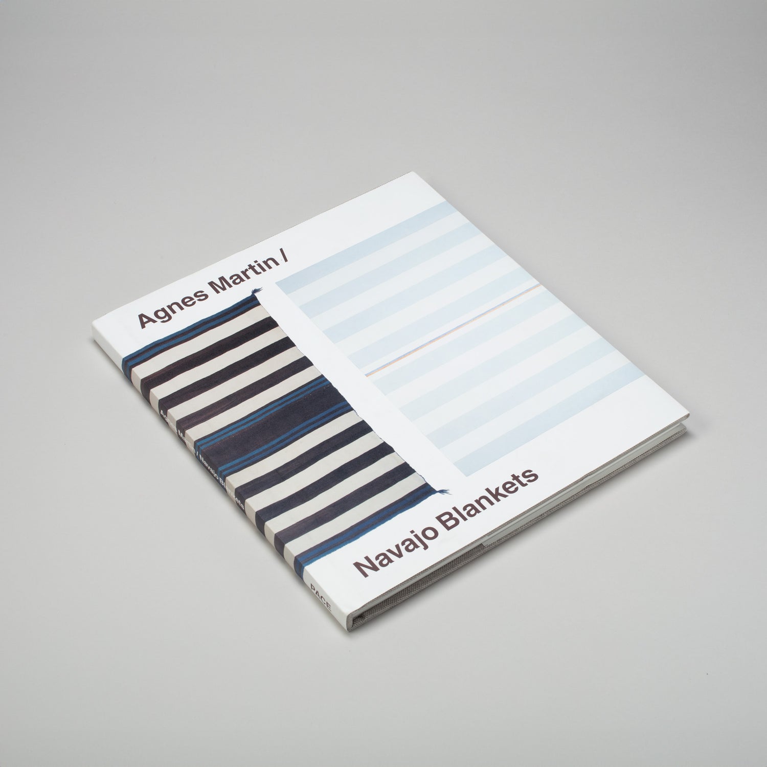 Agnes Martin Navajo Blankets is laying flat on a grey surface. The cover has a blue Navajo blanket next to a blue Agnes Martin painting.