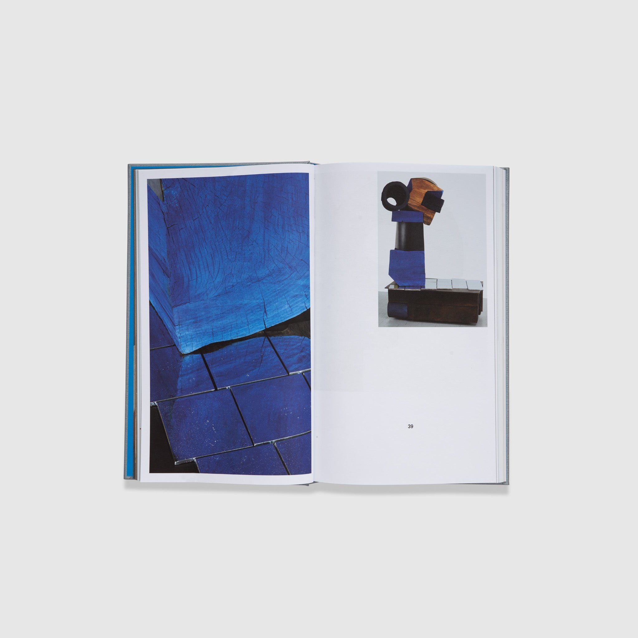 The book is open to two pages, with the left featuring a close up image of a blue wooden sculpture. The left page features a full shot of the same sculpture.
