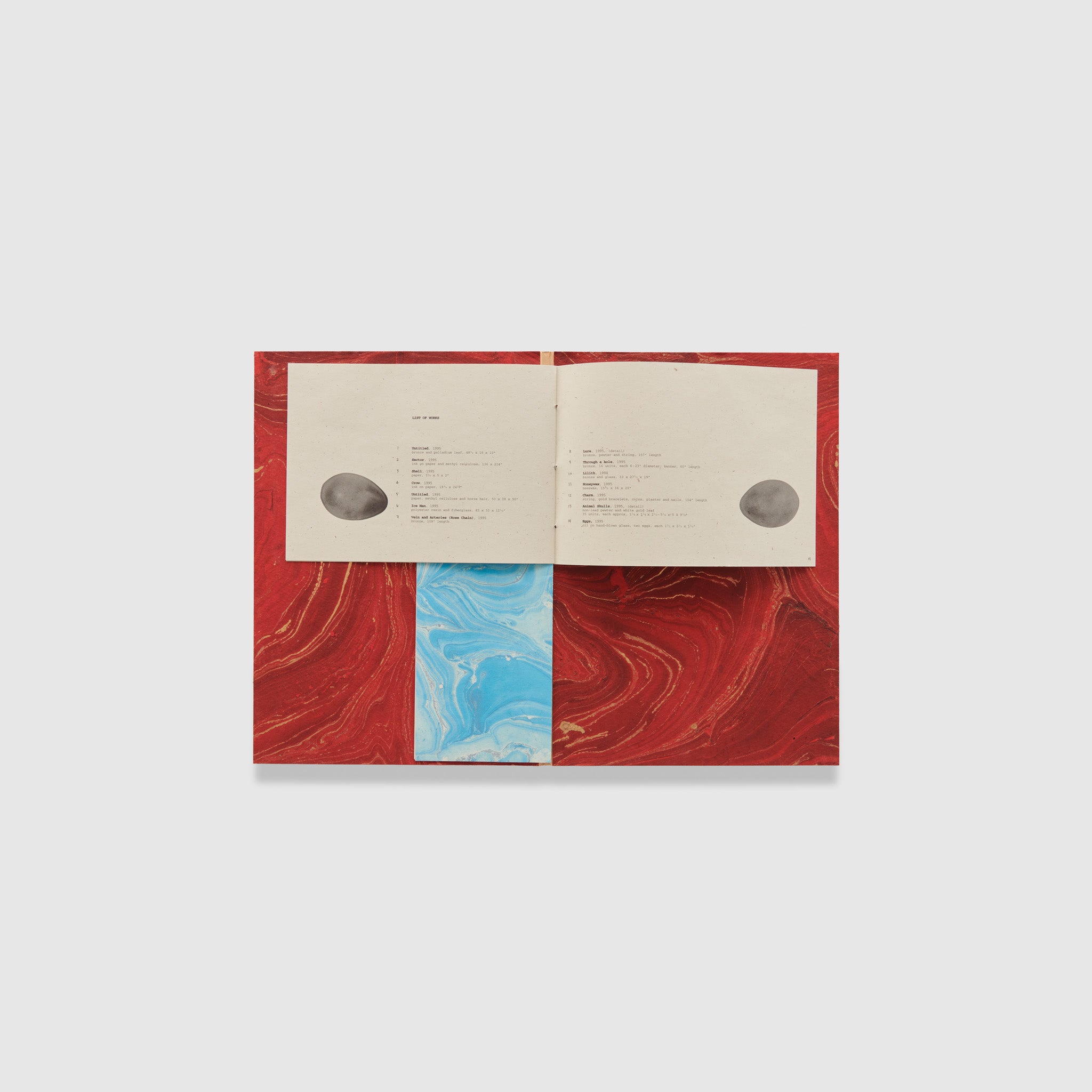 The book is open to two pages. The background is marbled red and goes across both pages.