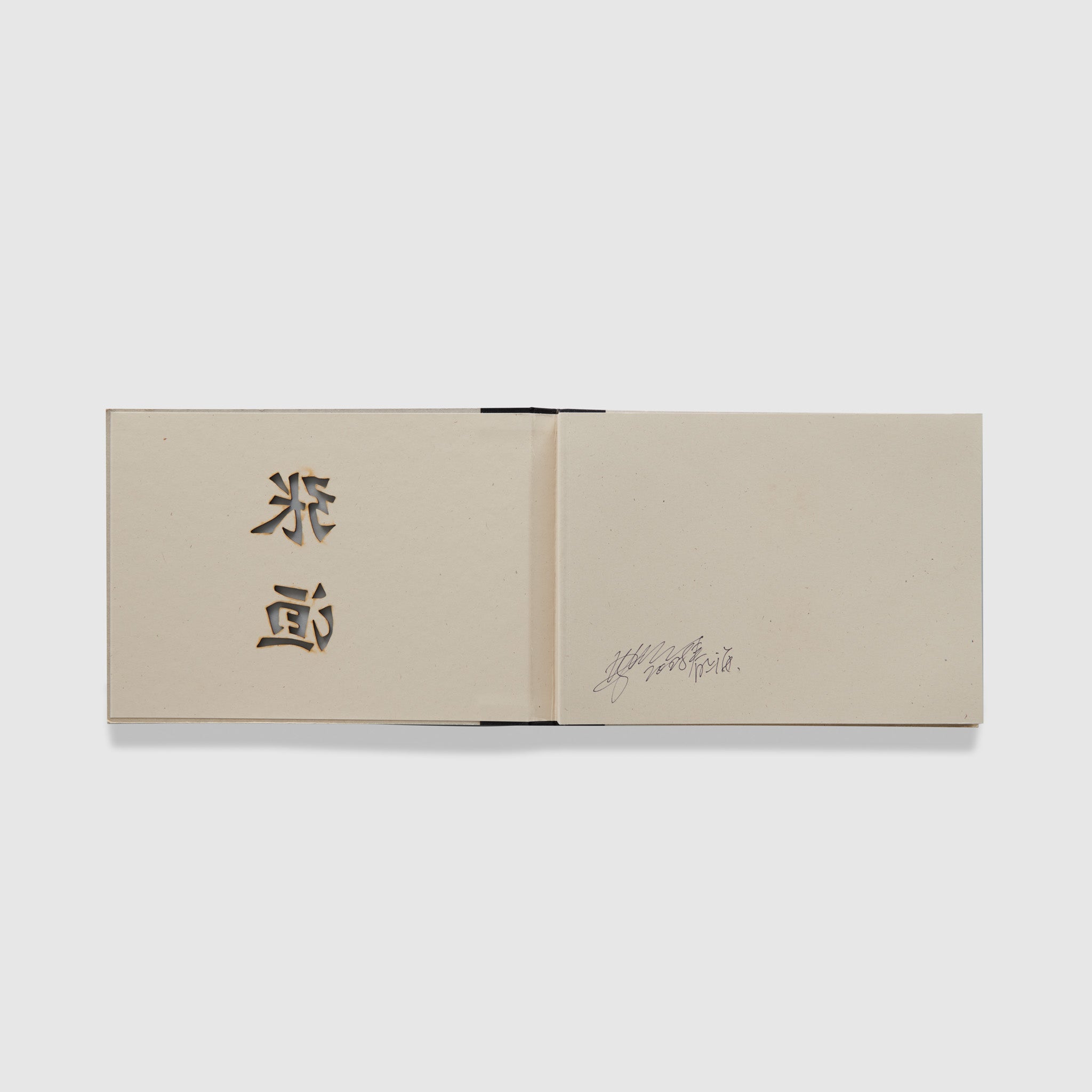 The book is open to two pages. The left page has the cutouts from the cover and the right page has a signature from the artist.