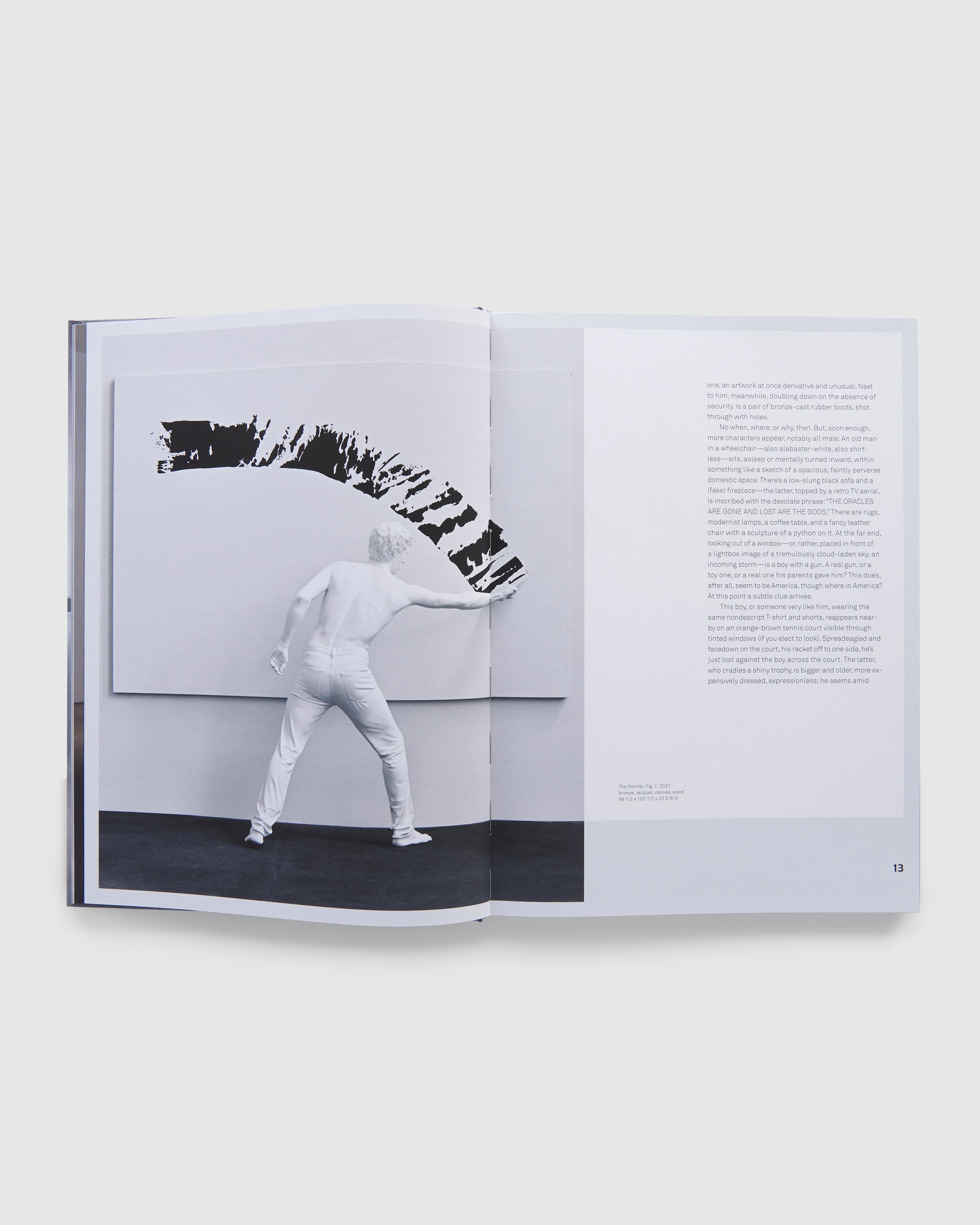 The book is open to two pages and has a photo of an Elmgreen & Dragset work on the left page and an essay in black text on the right page.