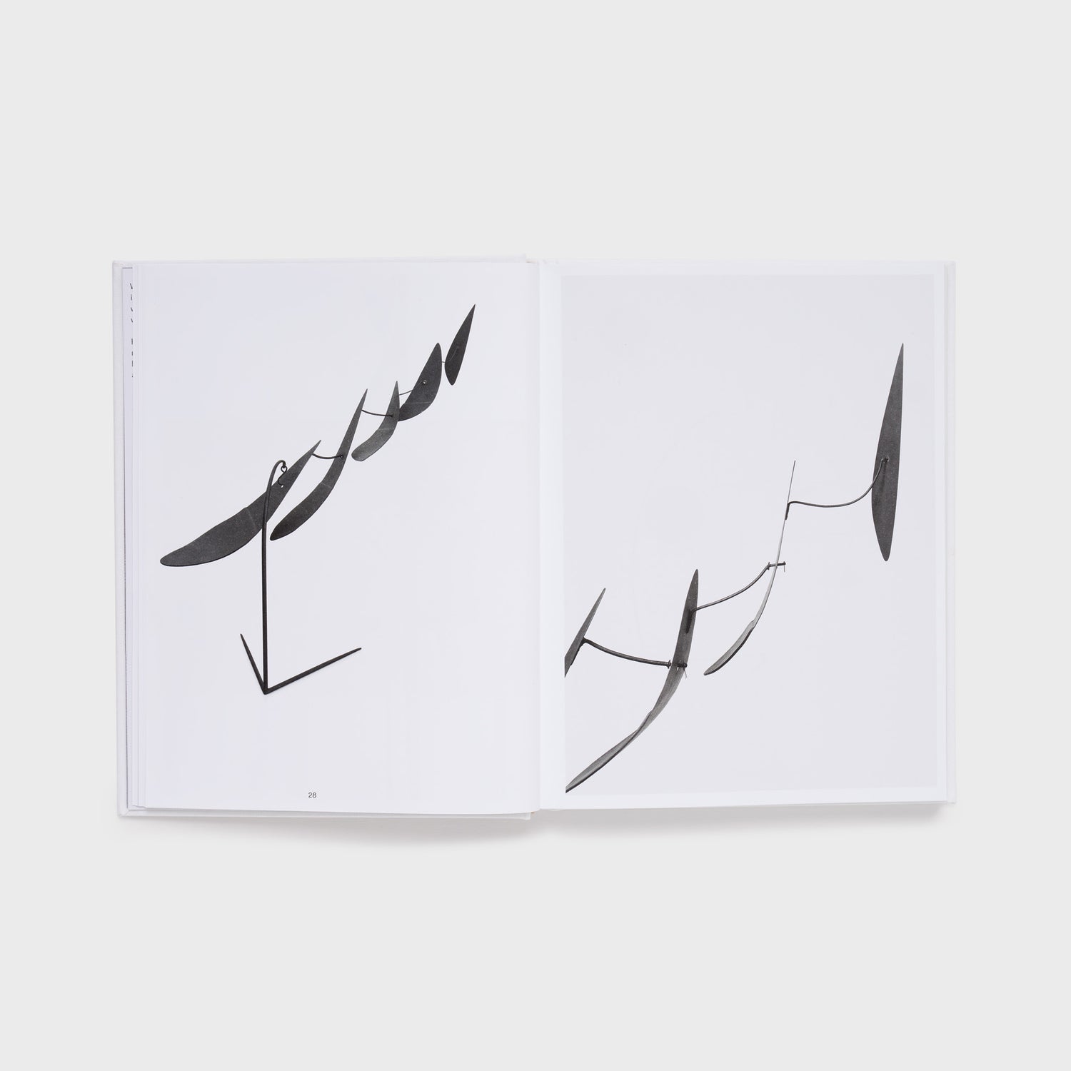 The book is open to two pages with an image of a black Calder mobile on the right page and the same work from a different angle on the left page.
