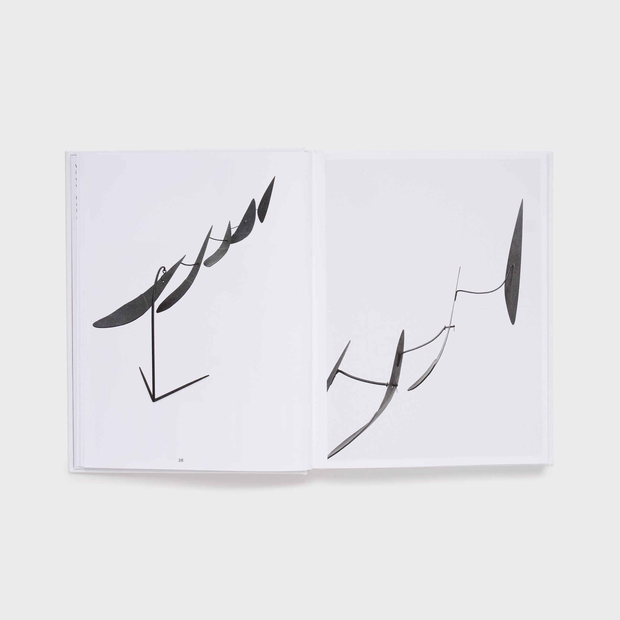 The book is open to two pages with an image of a black Calder mobile on the right page and the same work from a different angle on the left page.