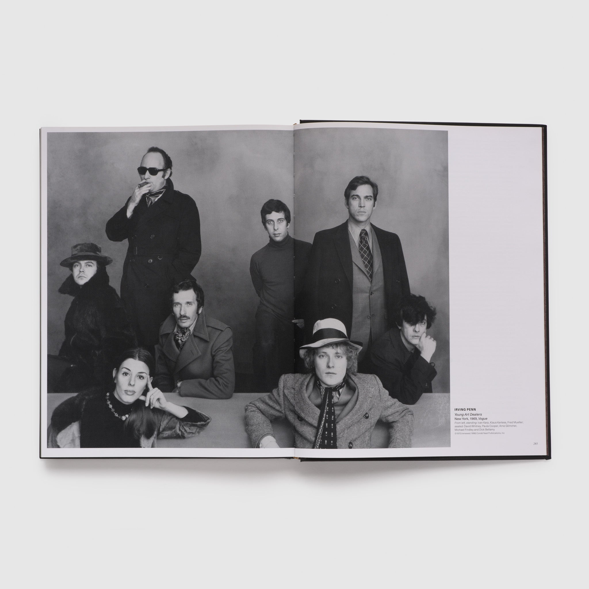 Two page spread of a black and white photograph of eight art dealers, taken by Irving Penn.