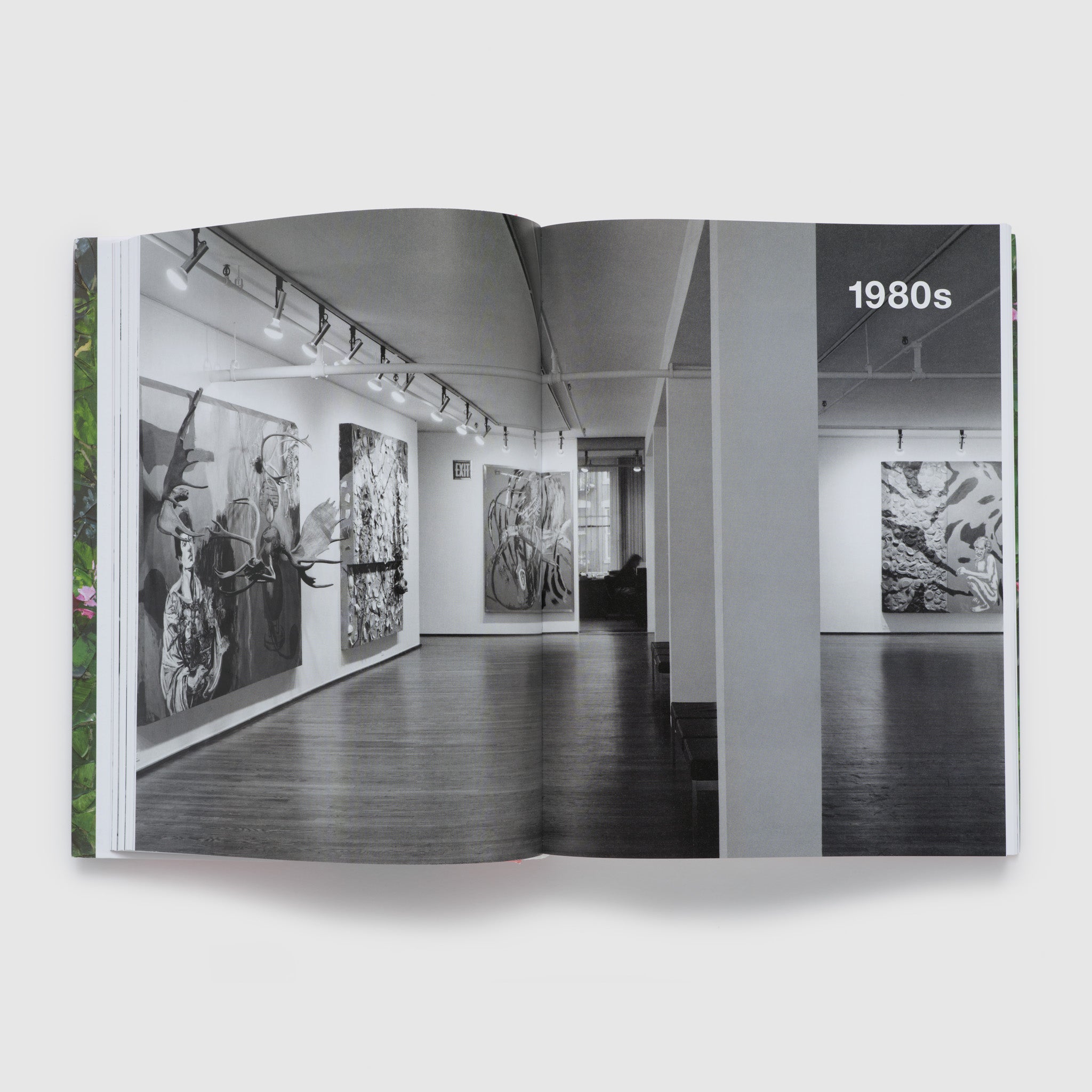 The book is open to two pages. There is a black and white image is a Schnabel exhibition across both with 1980s written in white font on the upper right hand corner.