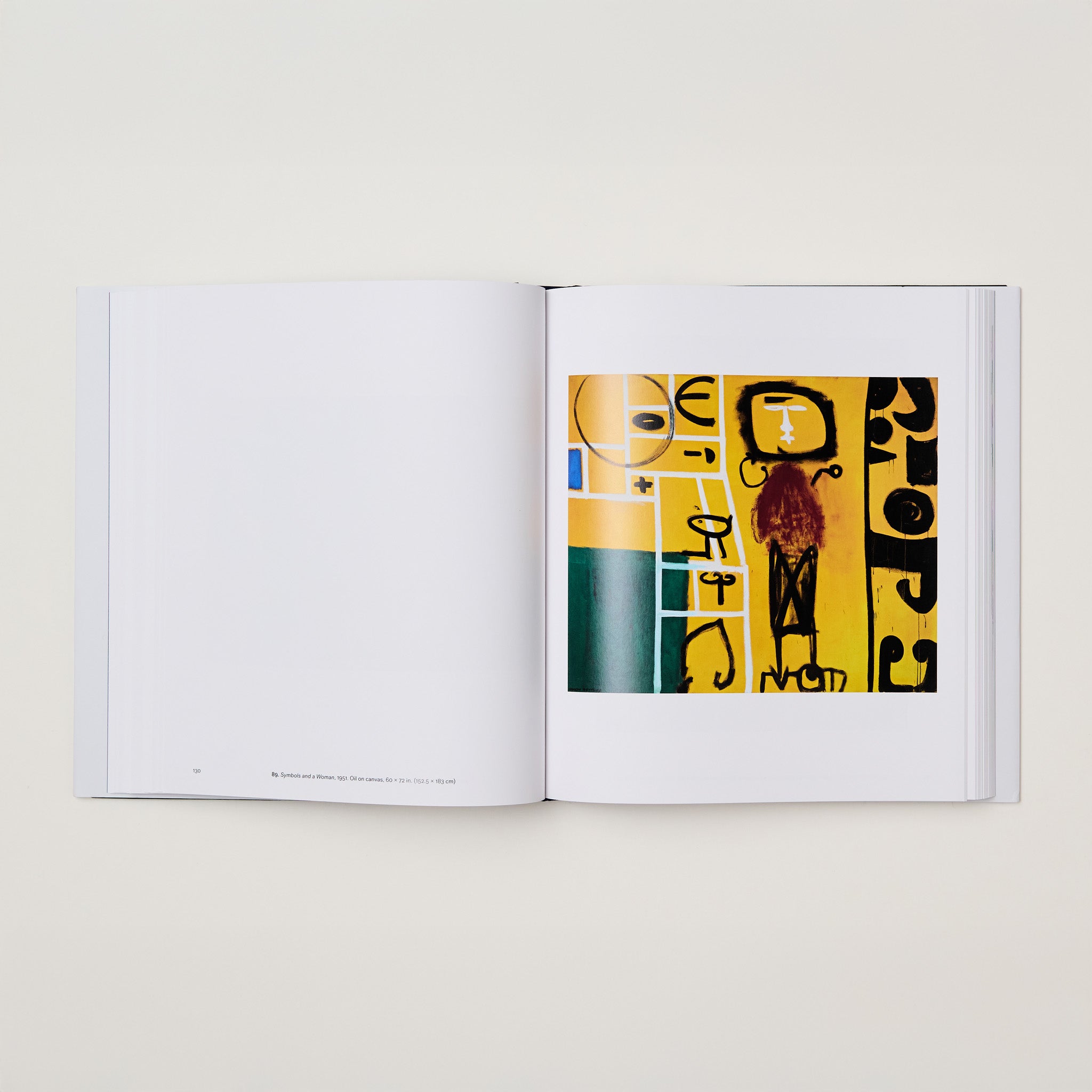 The book is open to two pages. The left page is blank with some black text at the bottom. The right page has a yellow, black, and white Gottlieb painting.