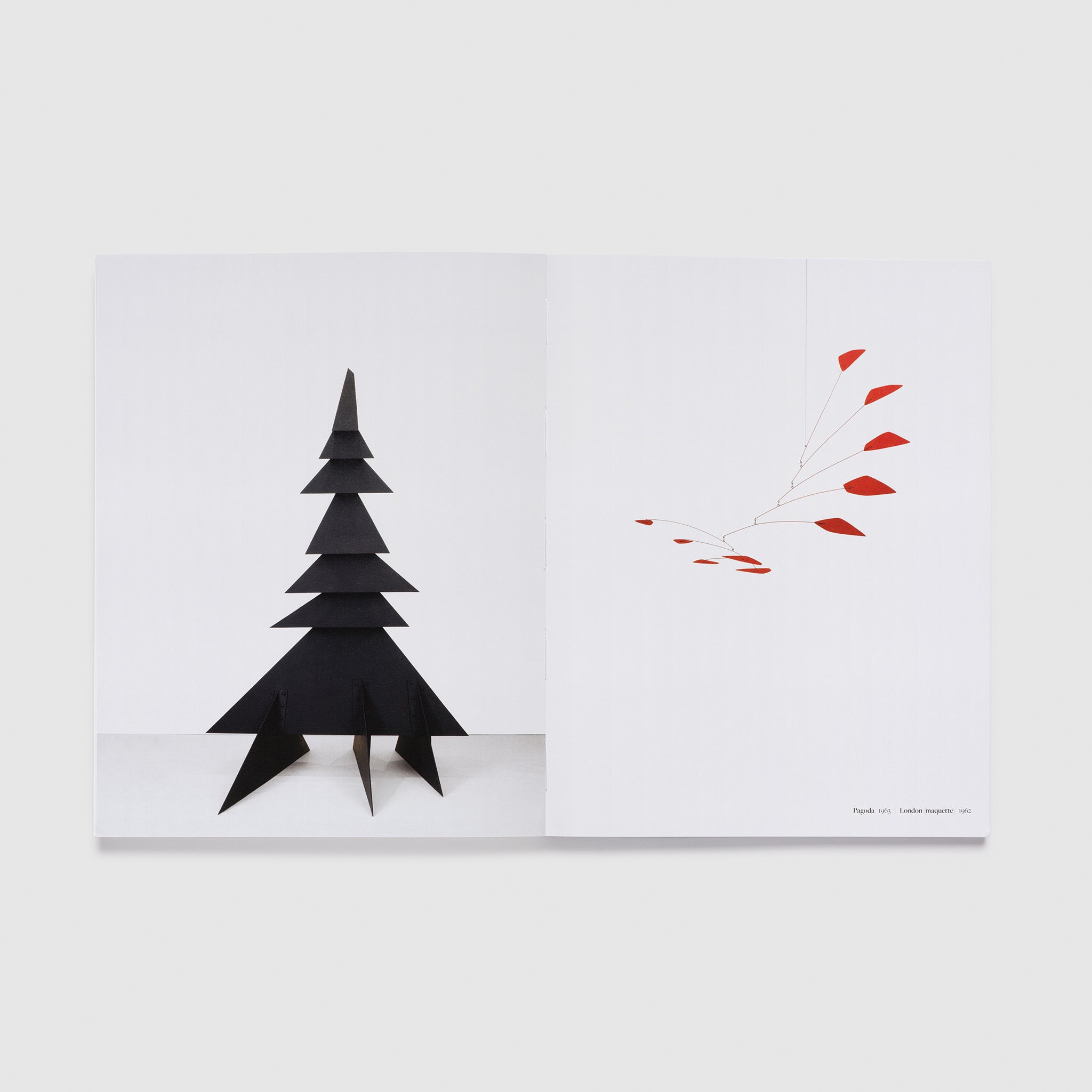 The book is open to two pages with a red Calder hanging sculpture on the right page and a black tree like sculpture on the left page.