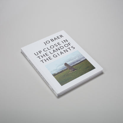 Jo Baer Up Close in the Land of Giants. The book has a white cover, black text, and an image of the artists work in a field.