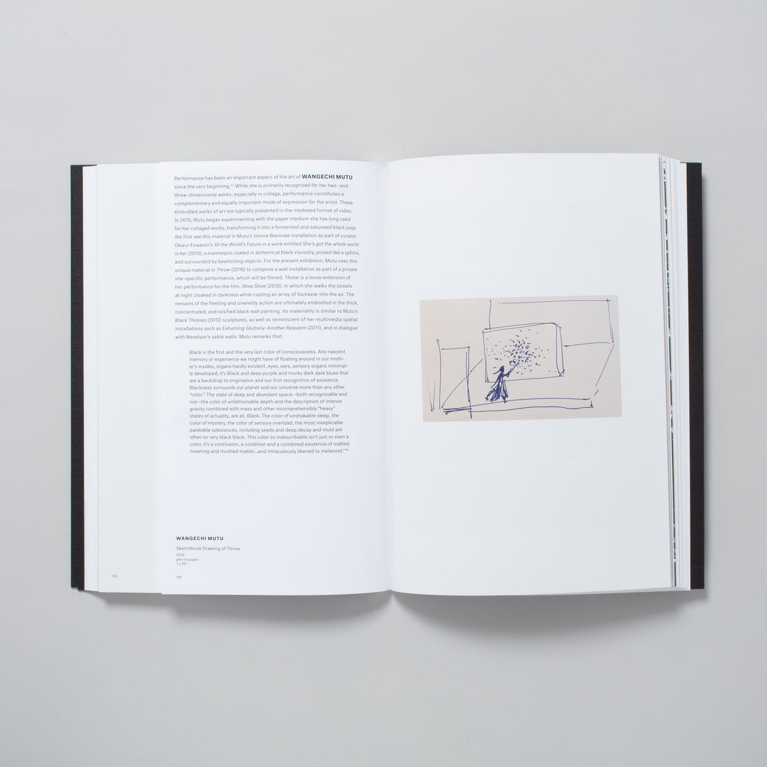 The book is open to two pages. The left page has an essay about Wangechi Mutu and the right page has an image of her drawing.