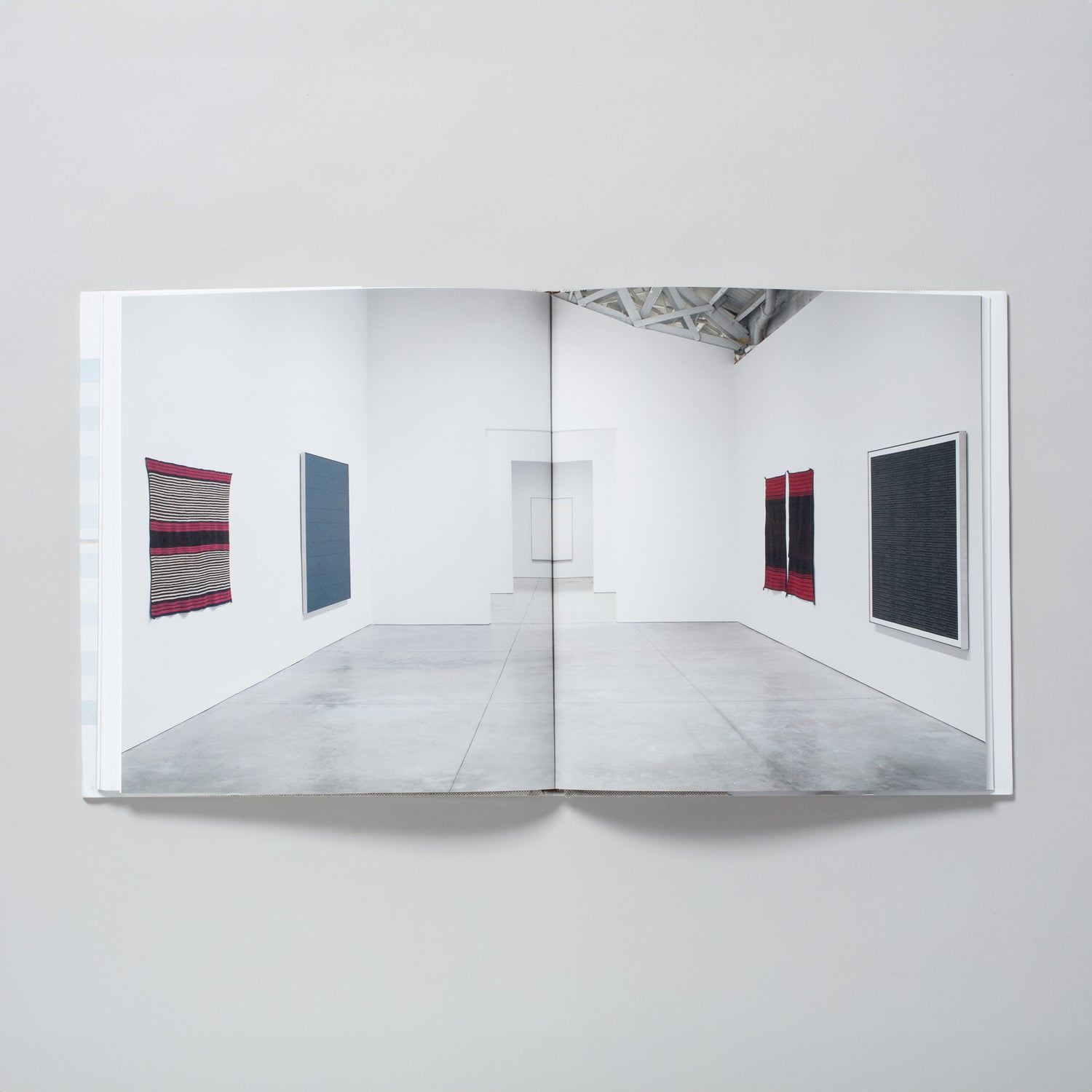 The book is open to two pages with one image of the gallery installation of the Martin works and Navajo blankets across both. 