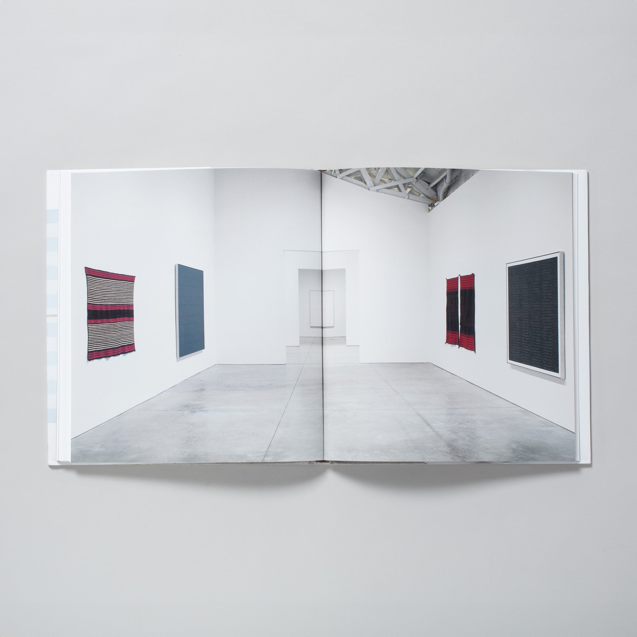 The book is open to two pages with one image of the gallery installation of the Martin works and Navajo blankets across both. 