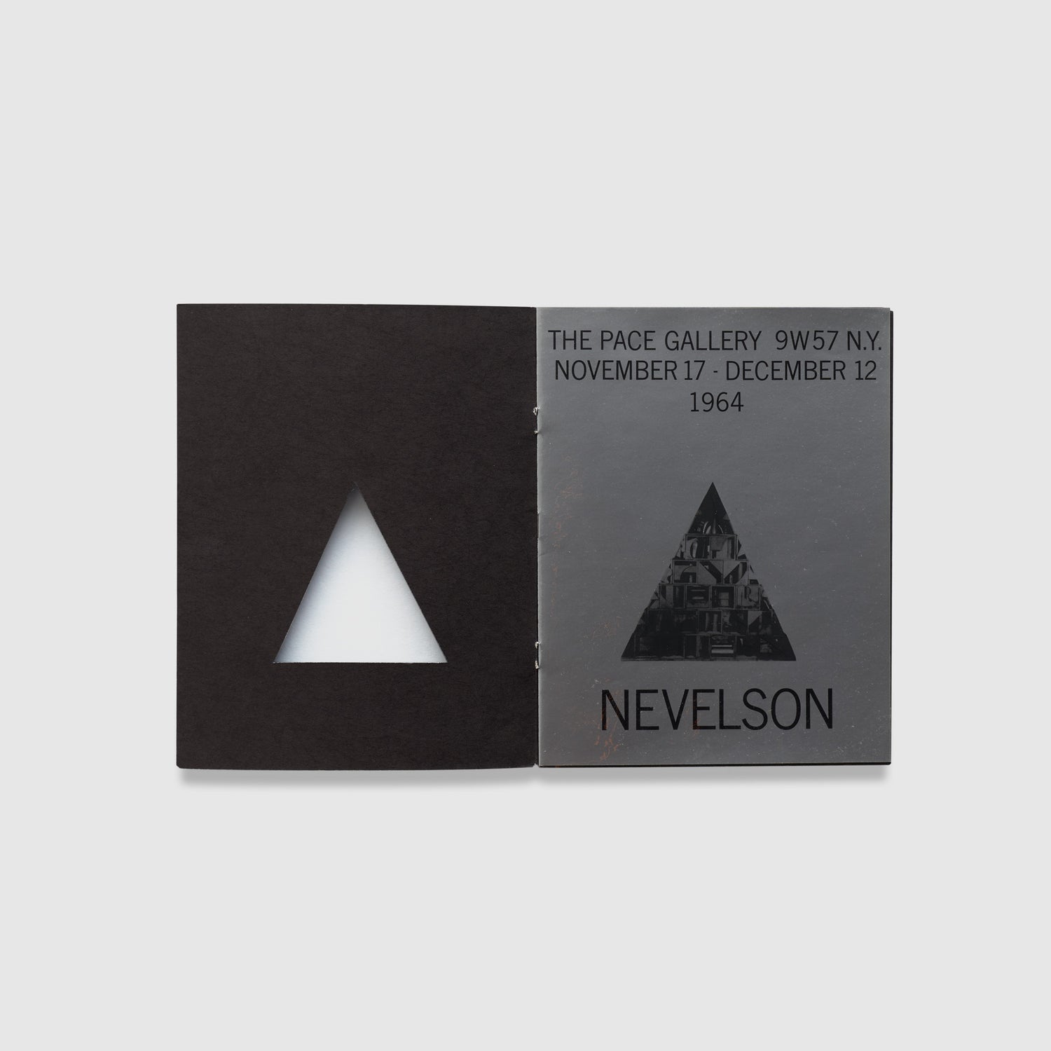 The book is open to two pages. The left page has a triangular cutout and a black background. The right page has the exhibition information for the Nevelson show at Pace Gallery.