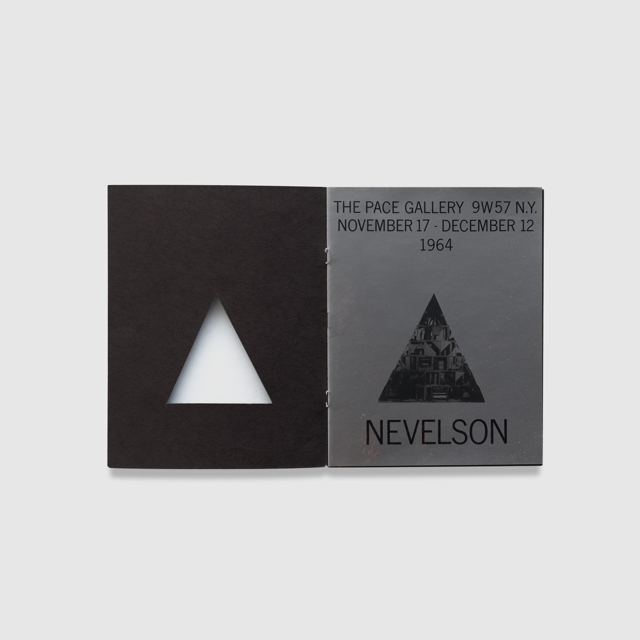 The book is open to two pages. The left page has a triangular cutout and a black background. The right page has the exhibition information for the Nevelson show at Pace Gallery.