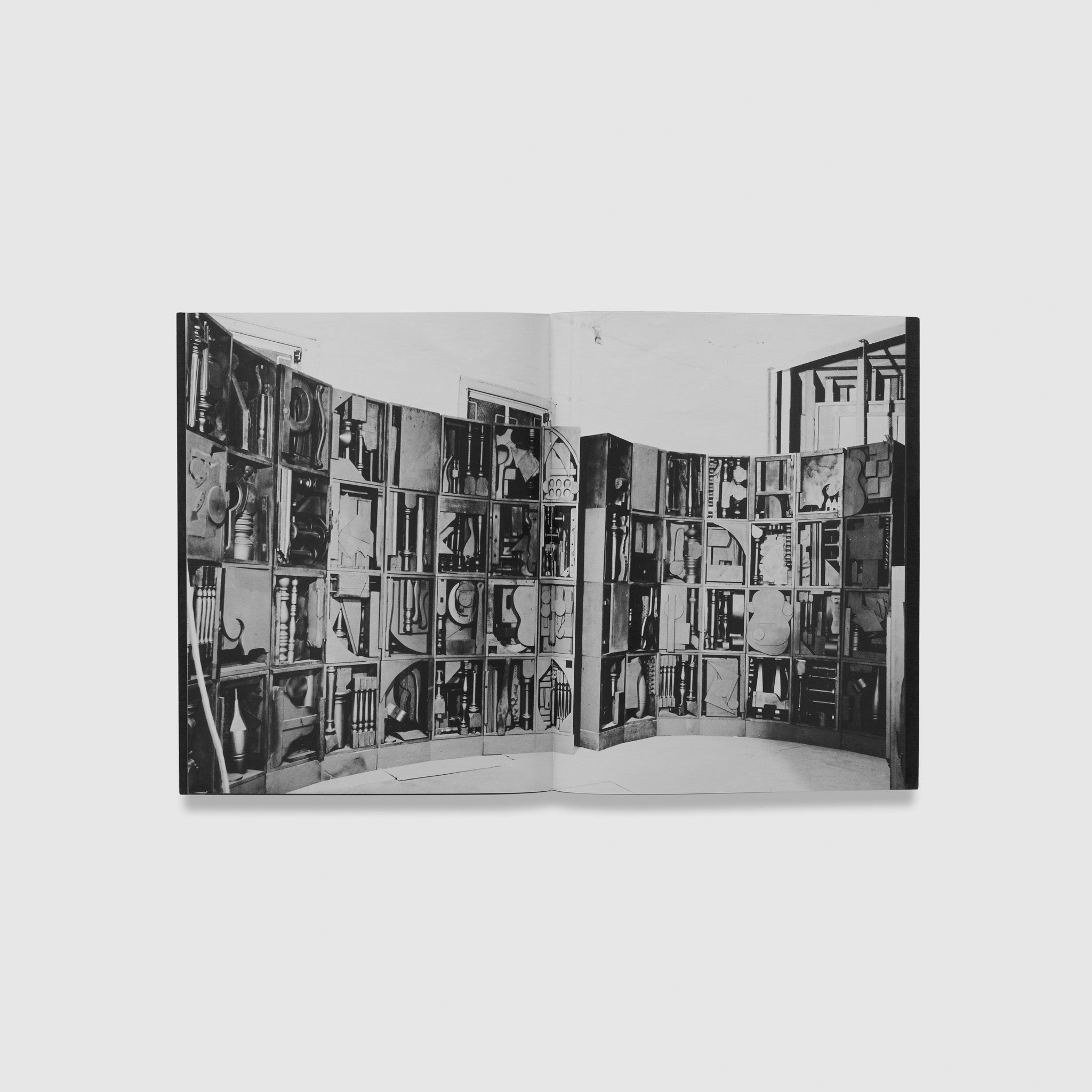 The book is open to two pages with a black and white photograph of a Nevelson work across both.