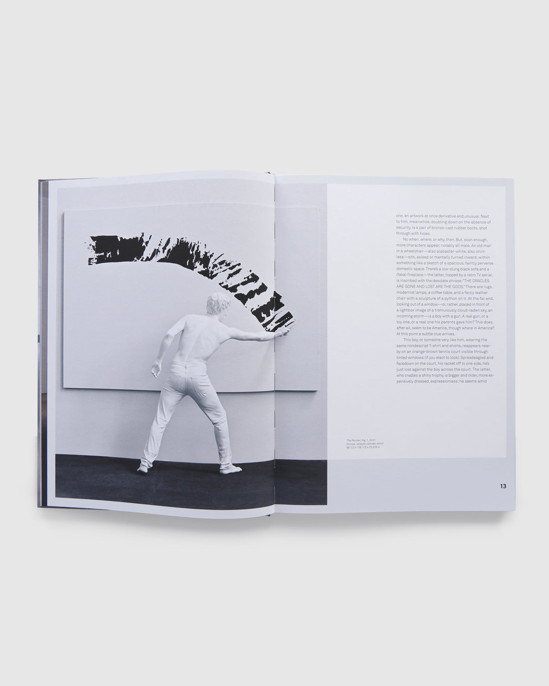 The book is open to two pages and has a photo of an Elmgreen &amp; Dragset work on the left page and an essay in black text on the right page.