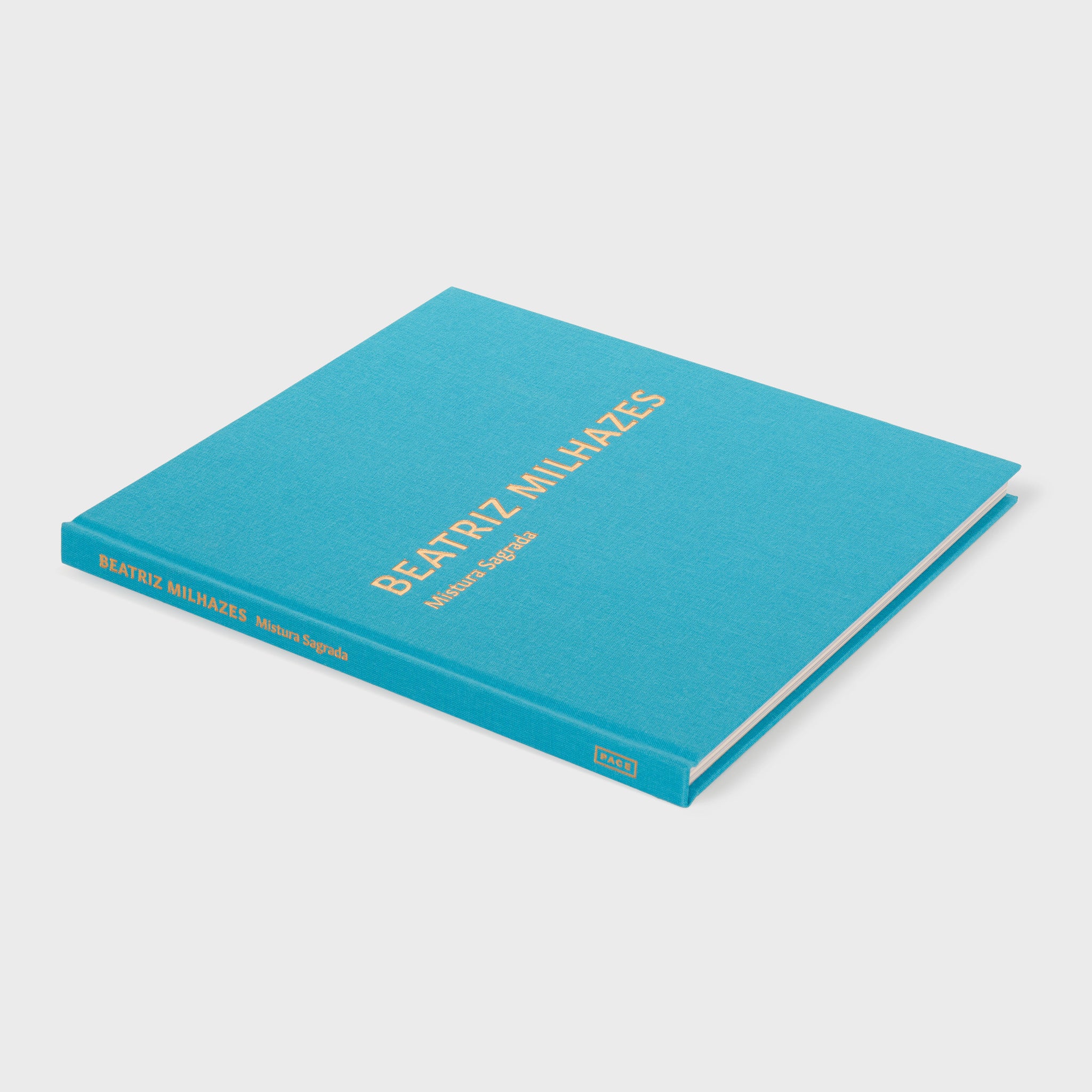 Beatriz Milhazes Mistura Sagrada is laying flat. The book has a bright blue cover with gold font. 